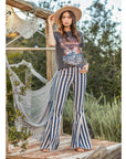 Model wearing Austin Striped Denim Flares standing outdoors with hammock in background