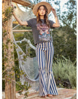 Outdoor shot of model wearing Austin denim flares next to hammock in relaxed boho setting