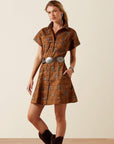 Woman wearing the Ariat Cody Dress, a brown western mini dress with subtle print, collar and short sleeves, styled with a silver concho belt and brown boots