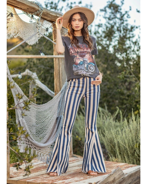 Model wearing Austin Striped Denim Flares standing outdoors with hammock in background