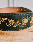 Detail of hand-painted floral tooling on a black leather belt with Western buckle