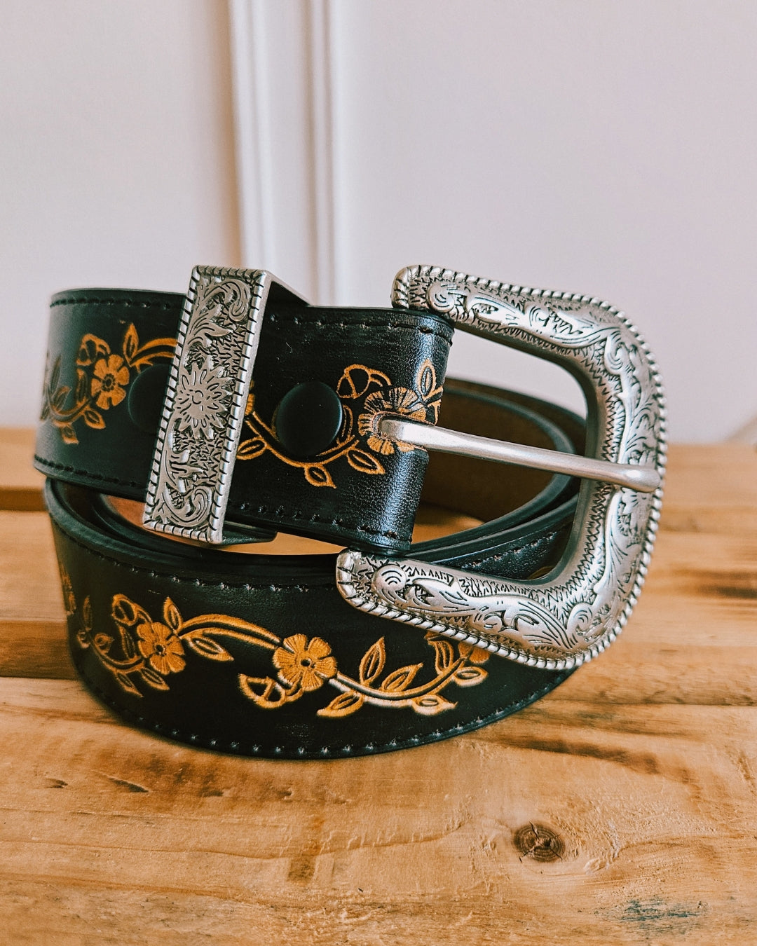 Black floral tooled leather belt with hand-painted flowers and a silver Western buckle