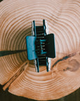 Top-down view of the Silver Engraved Western Hair Claw Clip open, showing the teal spring hinge mechanism on a rustic wood slice
