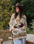 Woman wearing a patterned cardigan and cowboy hat outdoors