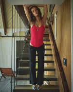 Model styled in Ribbed Western Buckle Red Bodysuit leaning on stair railing in warm, boho western home setting