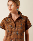 Close-up of the Ariat Cody Dress collar and button-front placket, showing the brown fabric's western cowboy print detail