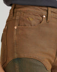 Close-up of Wrangler x Lainey Wilson brown chap jeans showing copper rivets, front pocket stitching and chap panel detail