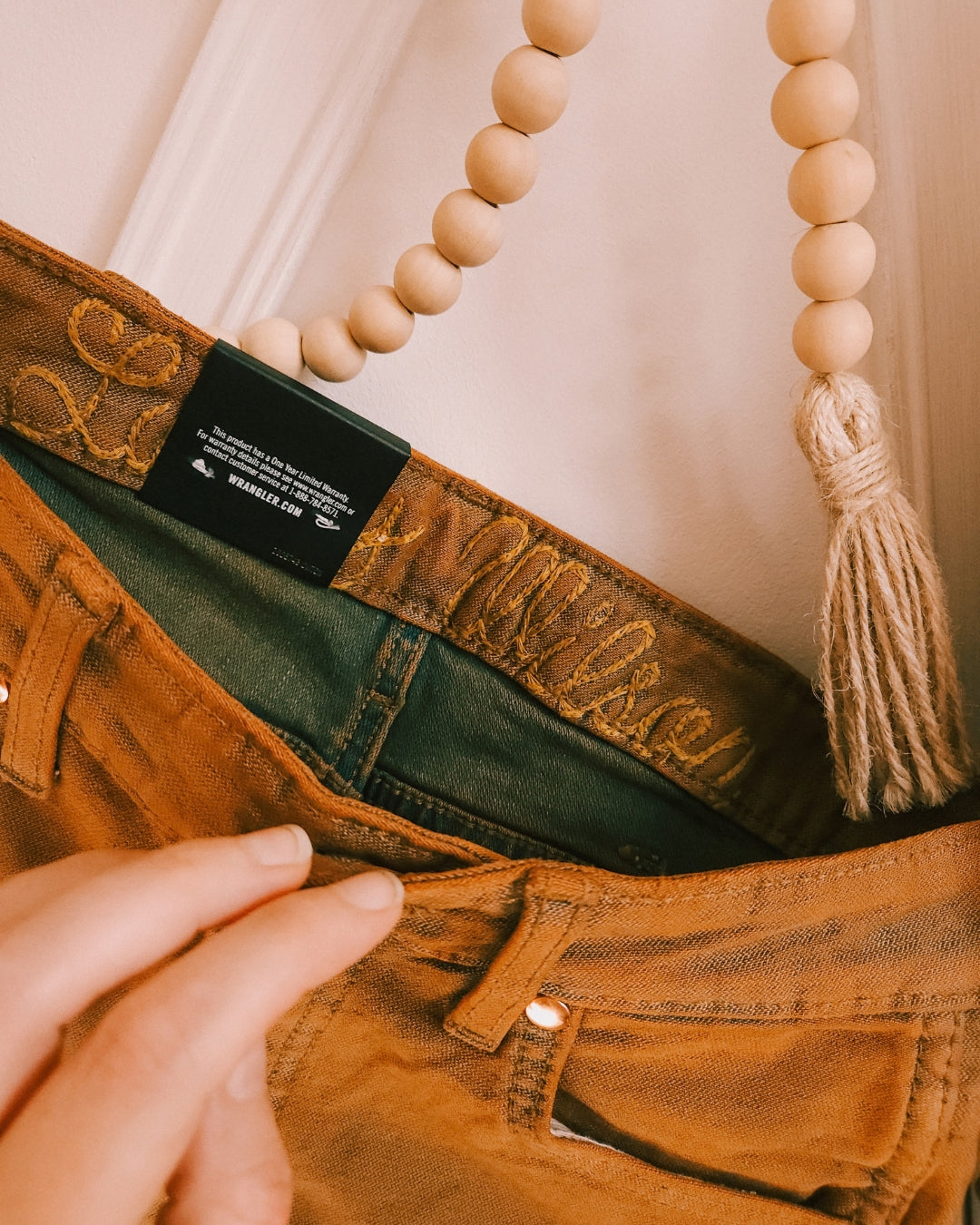 Close-up of the embroidery detail on Wrangler x Lainey Wilson brown chap jeans