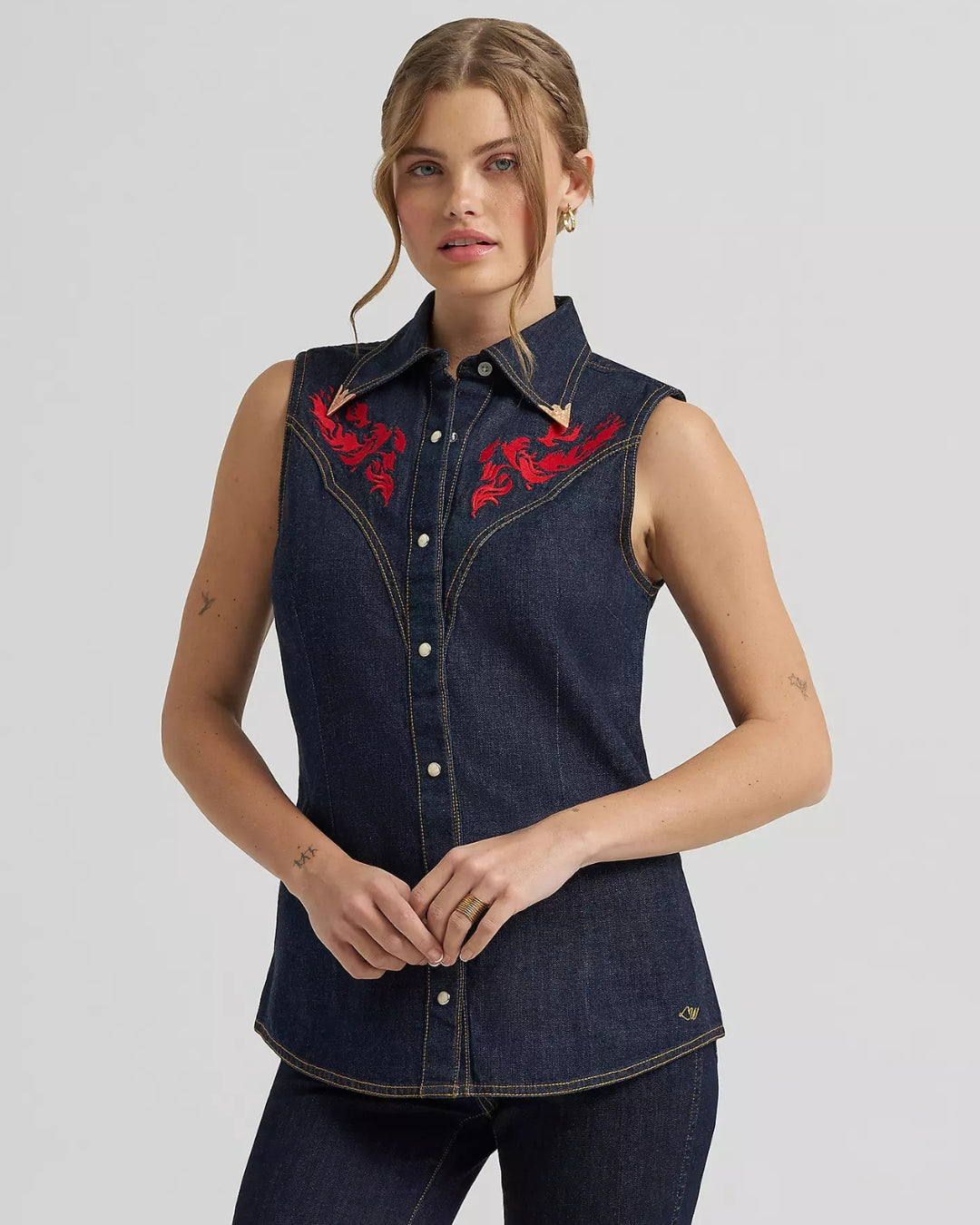 Model wearing Wrangler x Lainey Wilson embroidered sleeveless denim shirt, front view