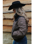Side view of the Wrangler Western houndstooth puffer jacket styled with a black cowboy hat and blue jeans against a timber wall